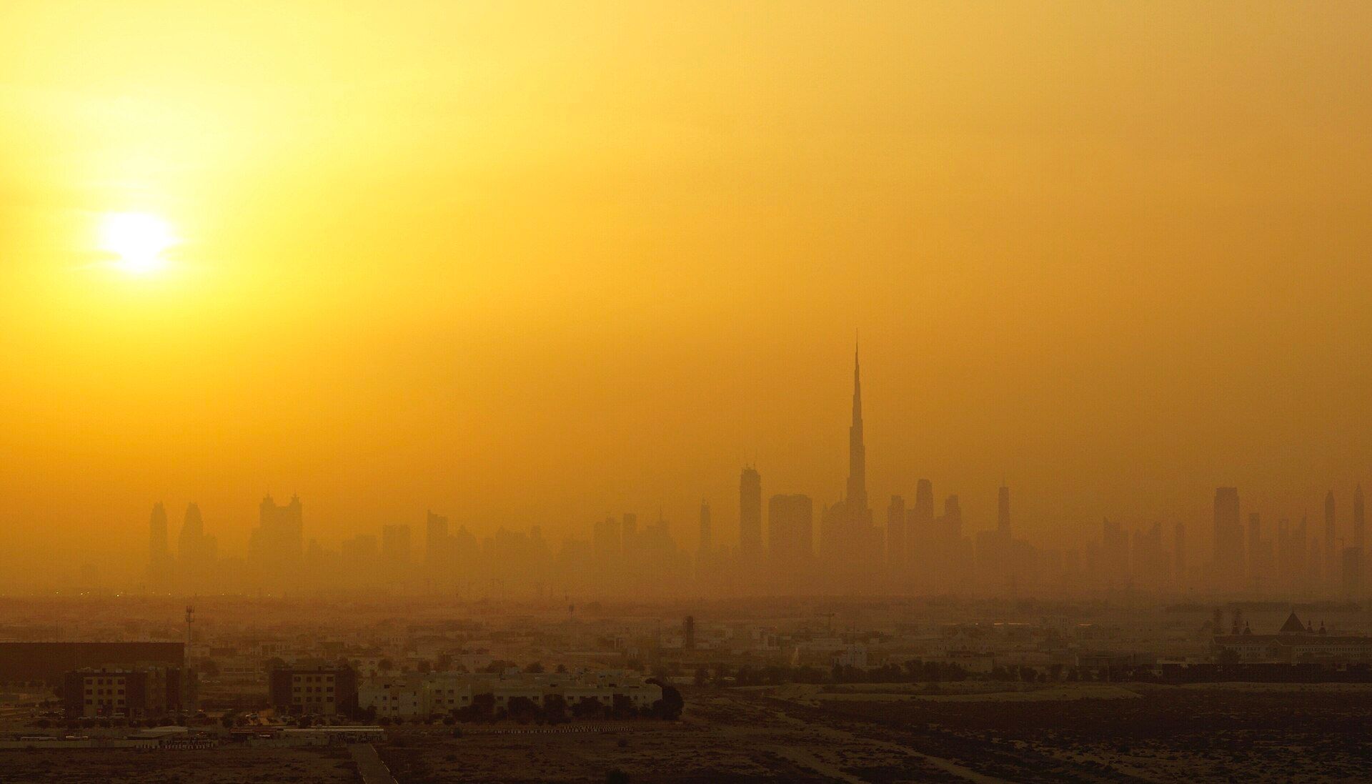 Dubai skyline with Burj Khalifa silhouetted in golden haze at dusk
