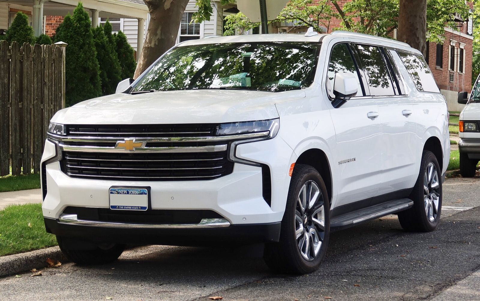 White Chevrolet Suburban SUV parked on a residential street, front three-quarter view