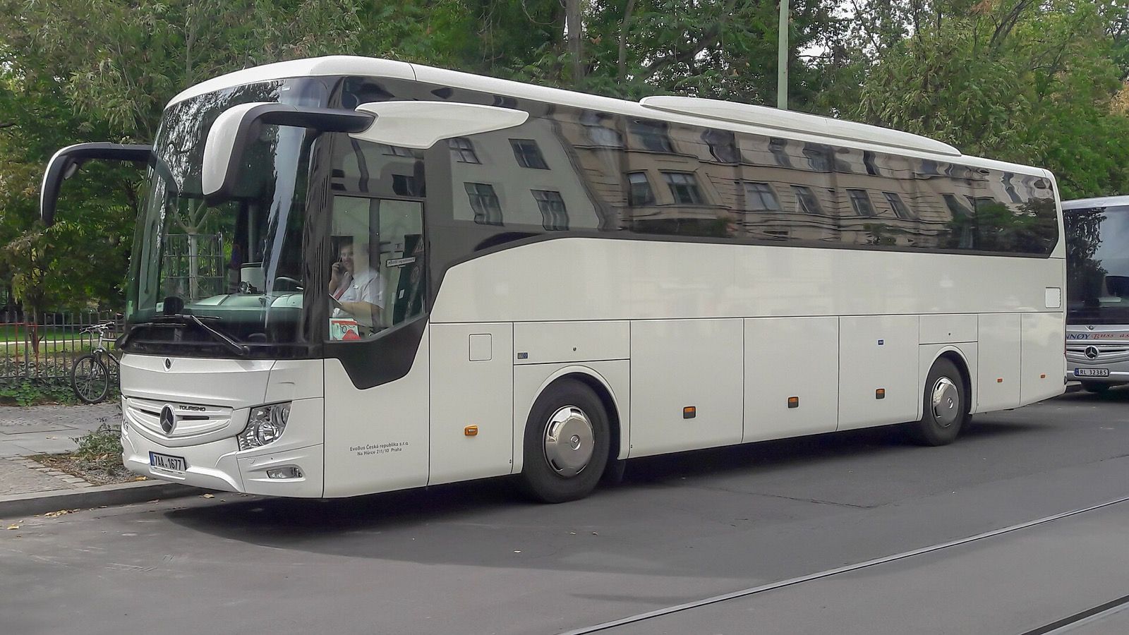 White Mercedes-Benz Tourismo full-size touring coach, front three-quarter view, parked on a street