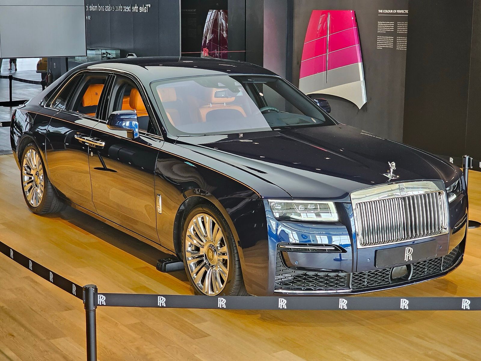 Dark blue Rolls-Royce Ghost sedan on display in a showroom, front three-quarter view