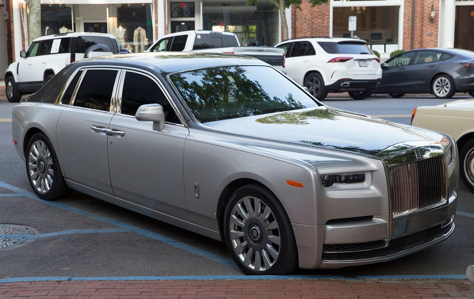 Silver Rolls-Royce Phantom with a black roof, front three-quarter view on a street